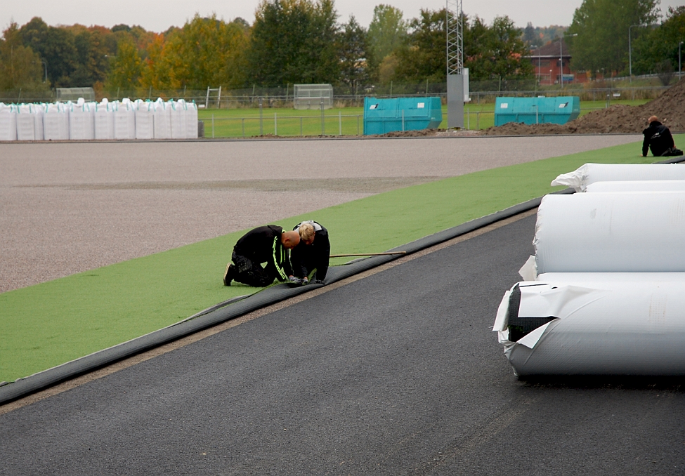 2014_1002_095948AA.JPG - Nu börjar konstgräset att läggas ut på grusbädden