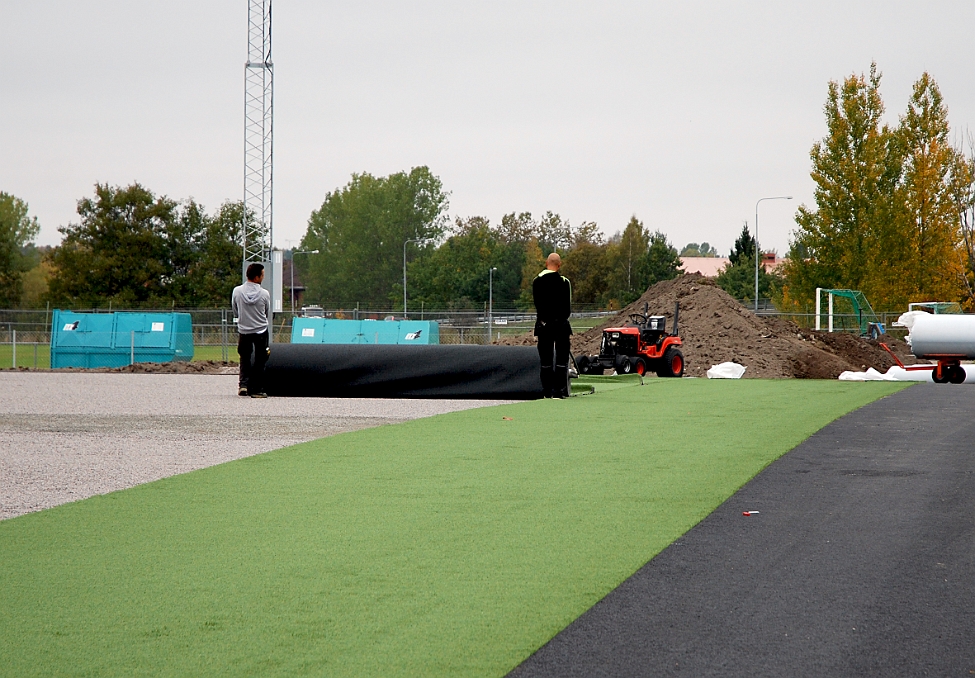 2014_1002_102357AA.JPG - Konstgräset rullas ut för hand